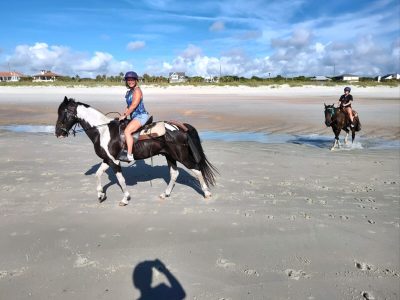 Two people on a beach horseback ride